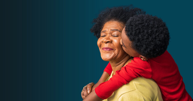 a young boy kisses his grandmother's cheek as she smiles