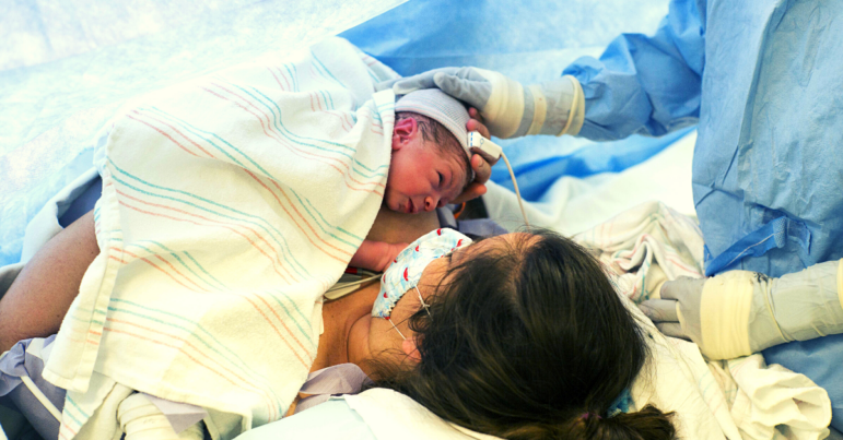 A new mom holds her baby right after delivering via c-section