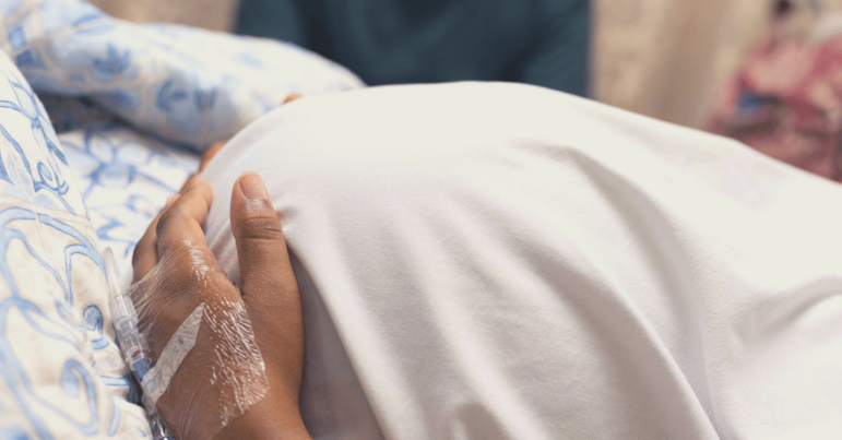 A pregnant woman in the hospital, holding her stomach